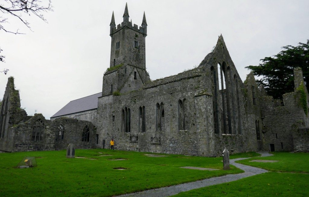The 13th century Ennis Friary in Ennis, County Clare, Ireland, on a dark October afternoon, with a pop of yellow. The incongruous pinnacles on the tower were added in the 19th century.