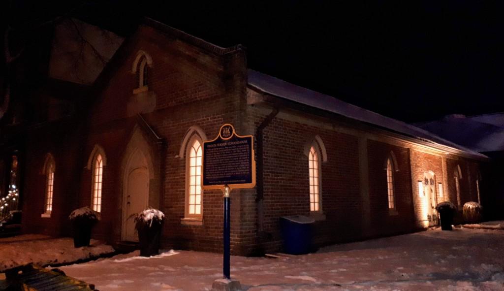 The 1848 Enoch Turner Schoolhouse, covered with snow, on a moonlit December night.