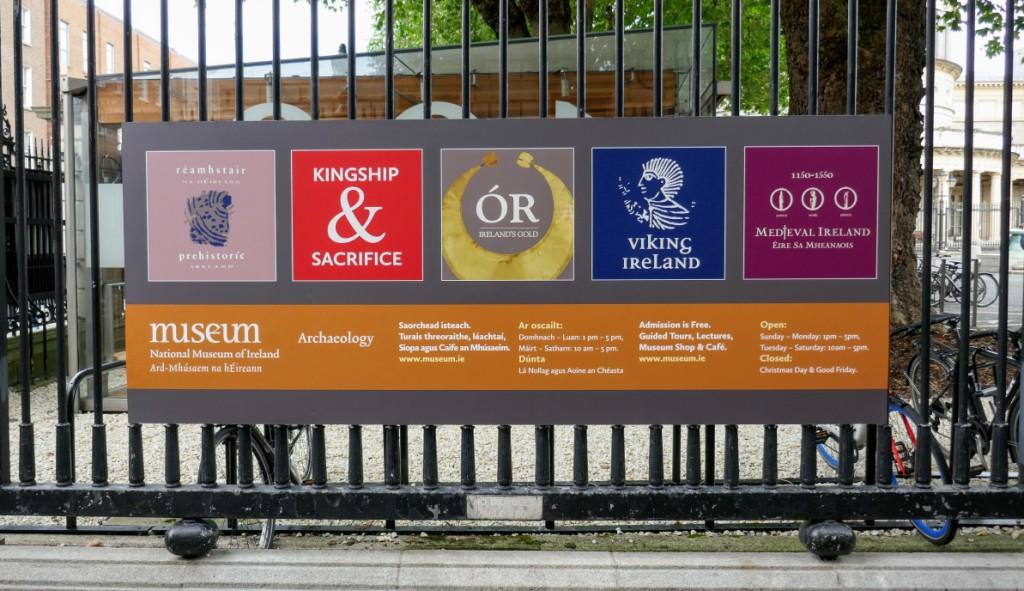 Colourful sign outside the National Museum of Ireland - Archaeology. You can see the round portico of the National Library in the background.